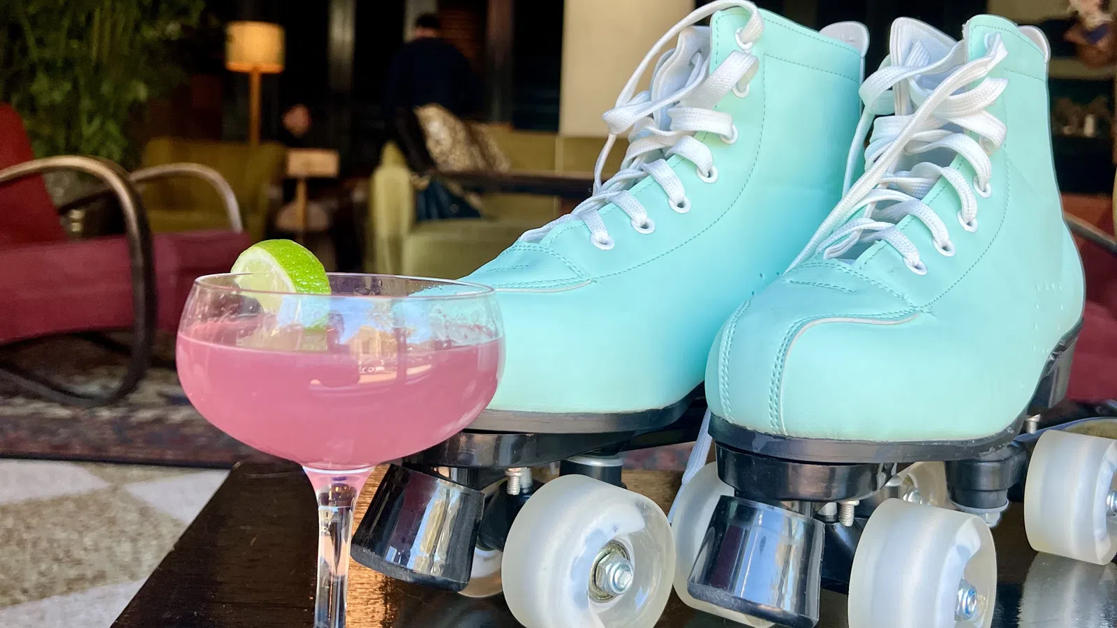 a glass of pink liquid next to a blue and white ice cream cone