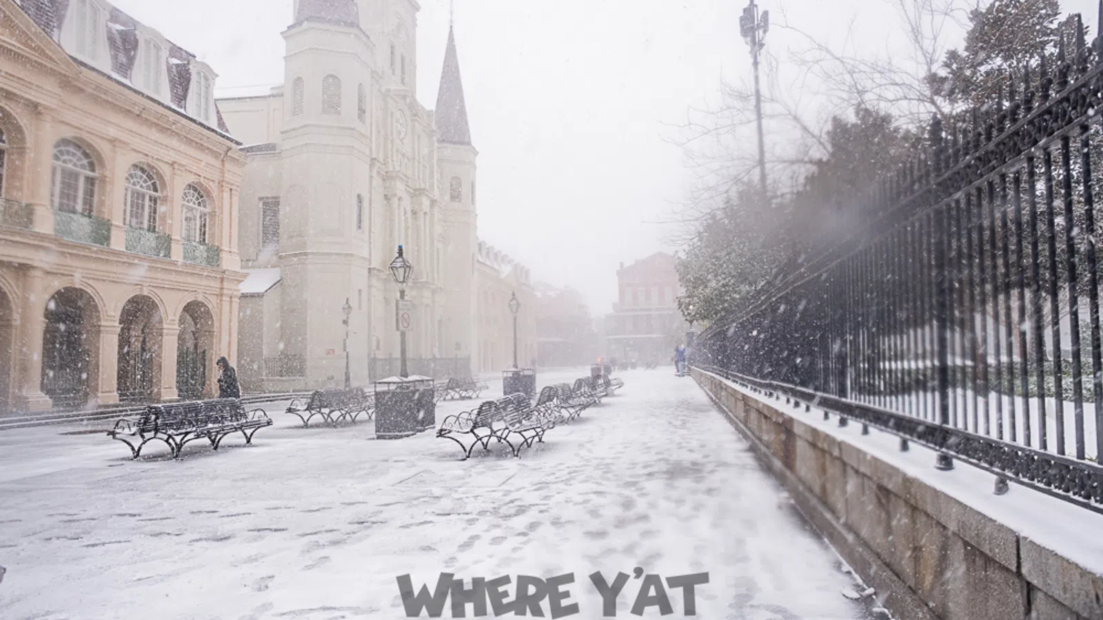 a snowy street with benches and buildings