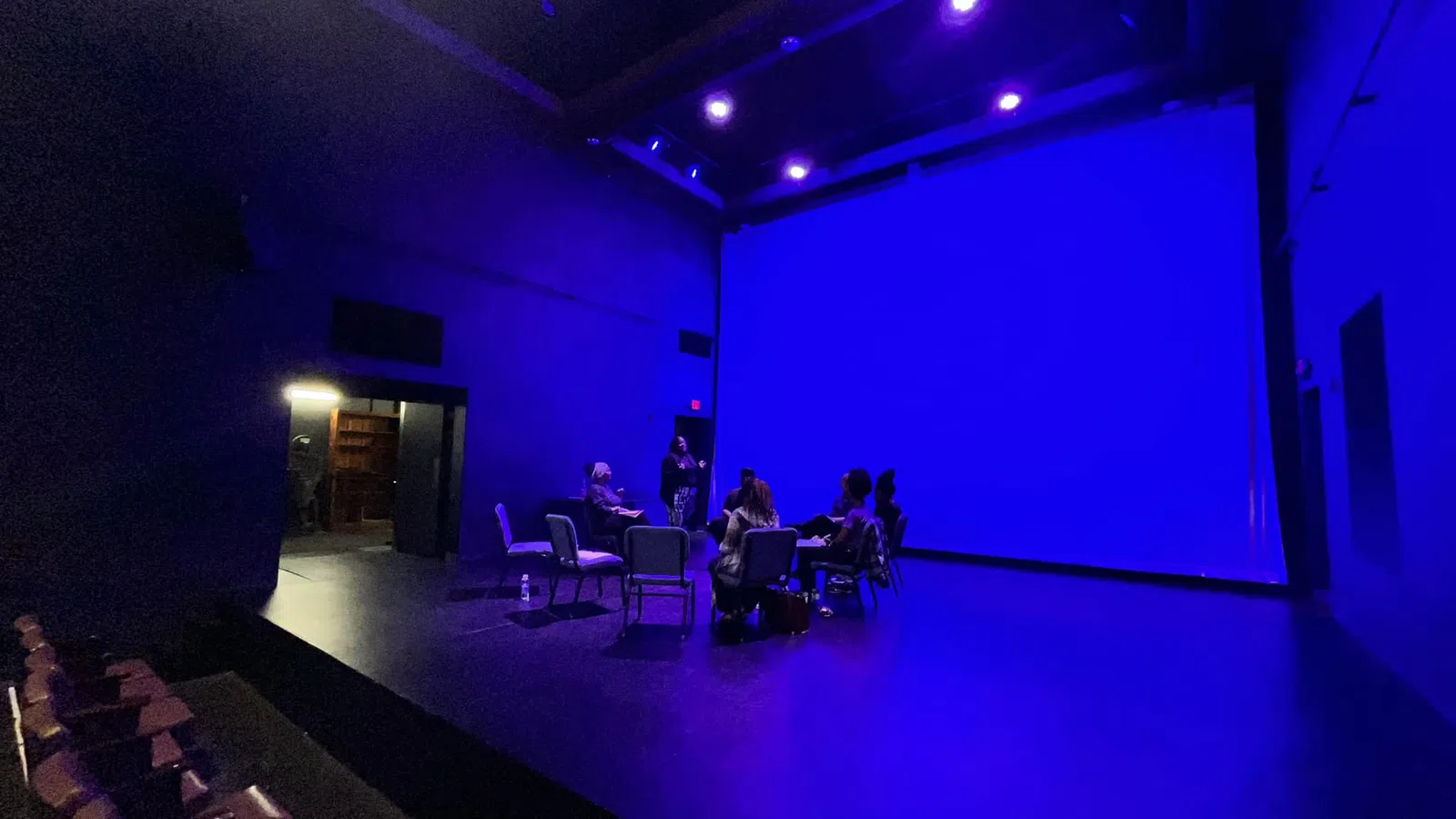 a group of people sitting in chairs in a room with blue lights