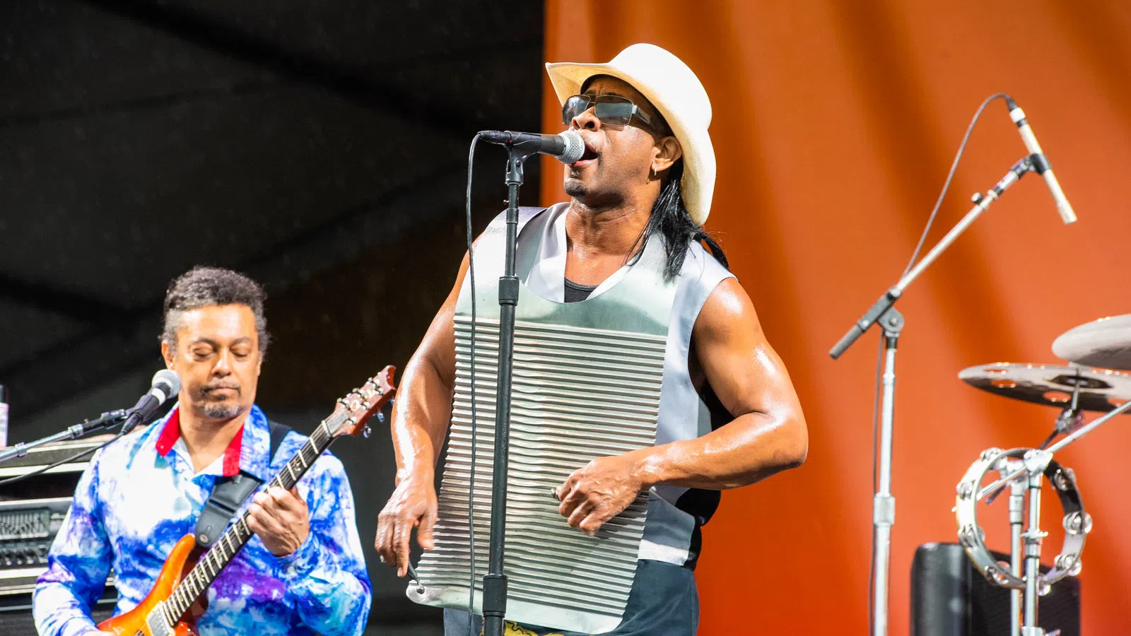 a person playing guitar next to a person singing into a microphone