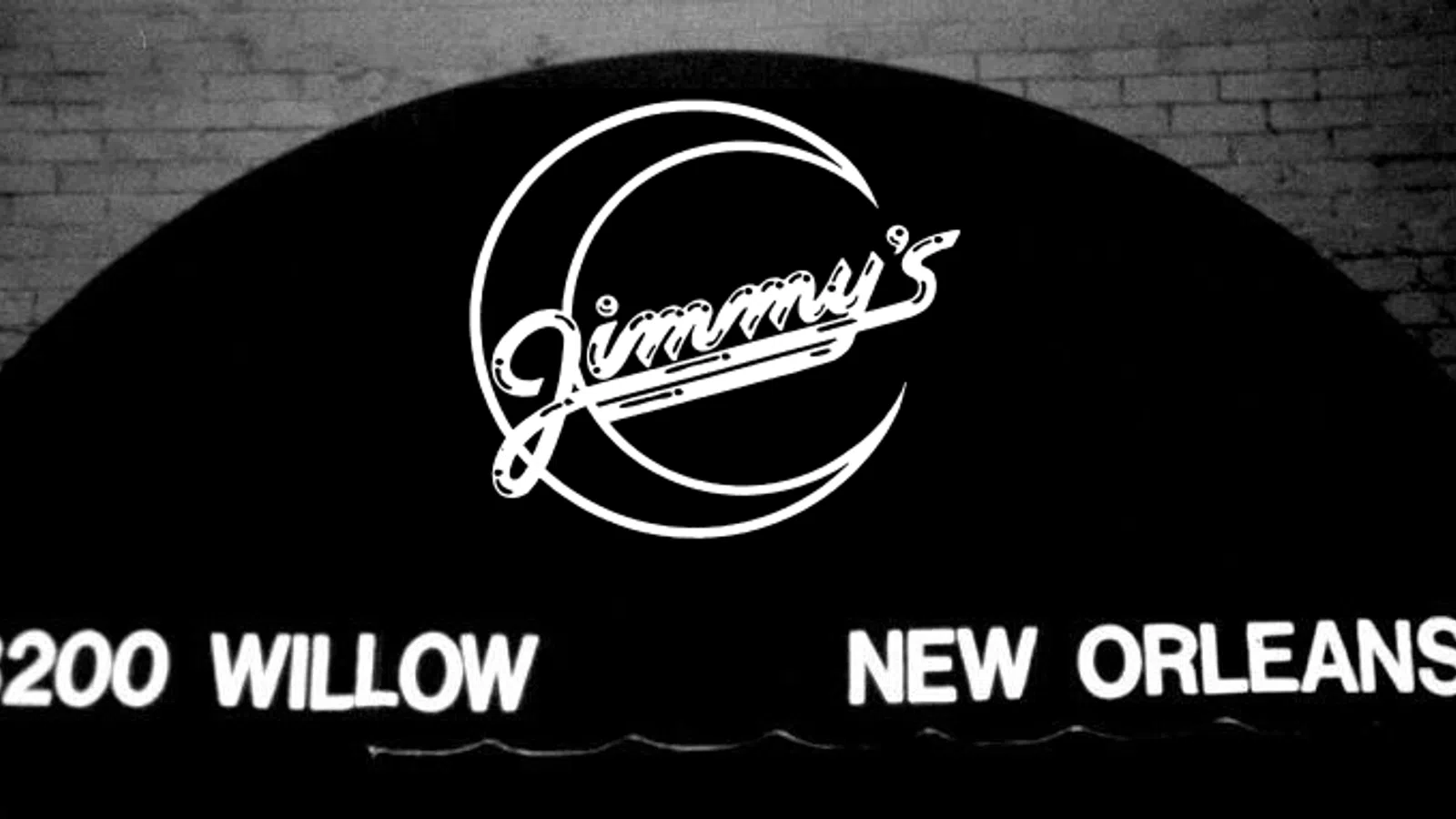 Black awning with white neon sign for Jimmy's at 8200 Willow in New Orleans on brick wall background