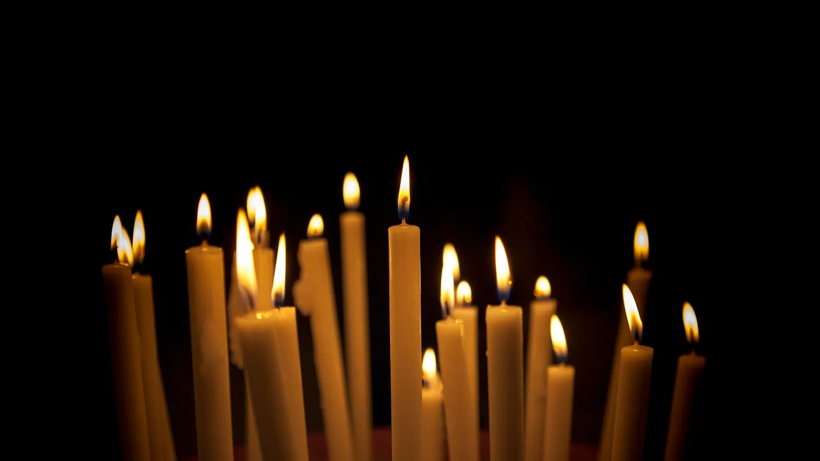 Multiple lit candles glowing against a dark background creating a warm, peaceful ambiance.