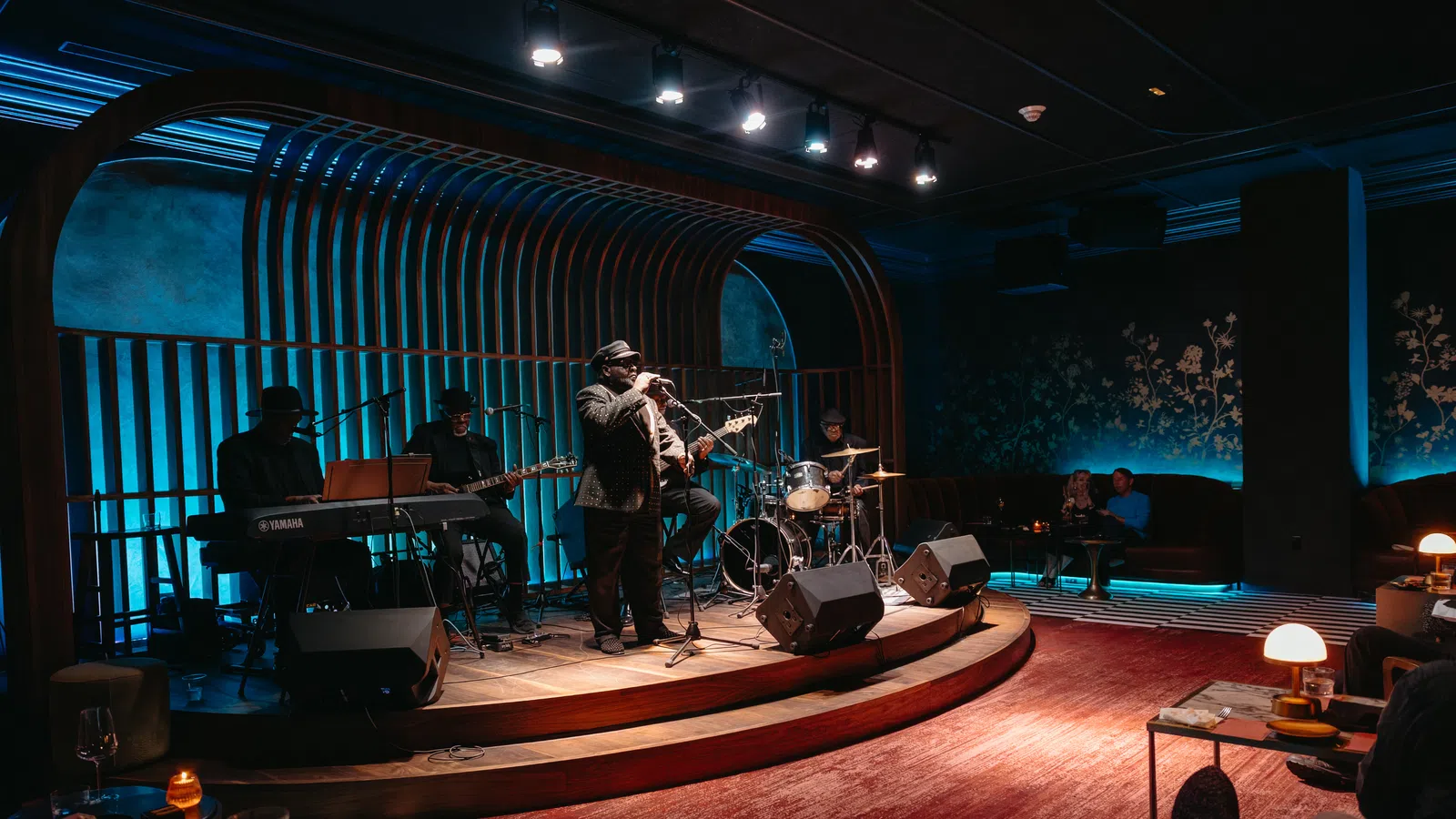 Jazz band performing live on stage in a stylish lounge with blue lighting and cozy seating.