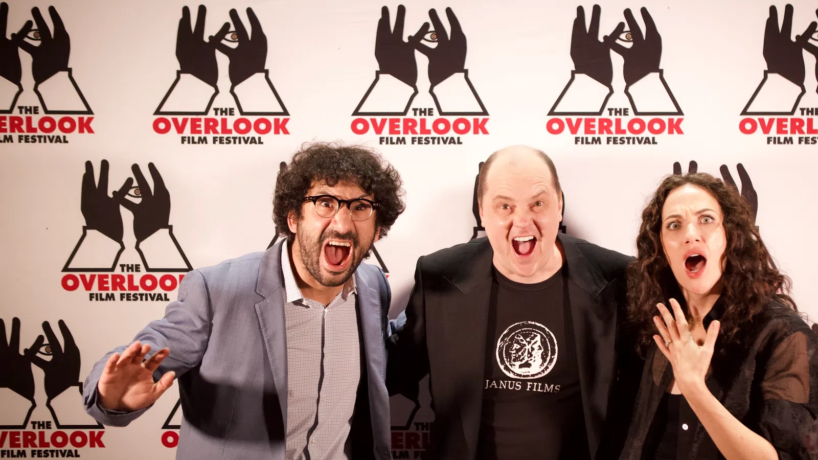 Three excited individuals pose in front of The Overlook Film Festival backdrop.