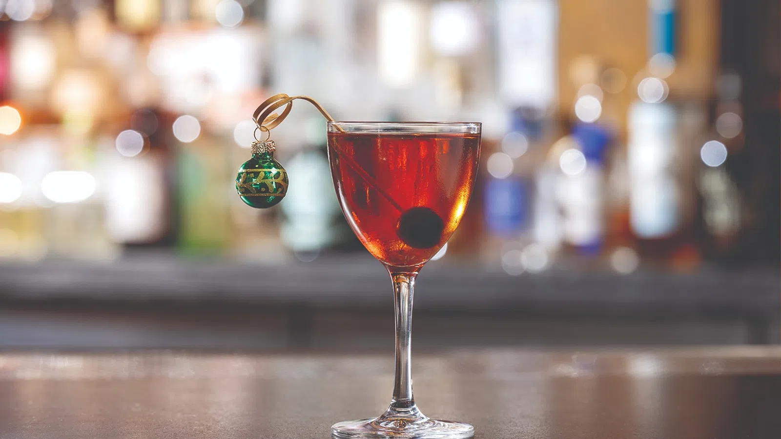 a glass with a red liquid and a green key chain on a wooden surface