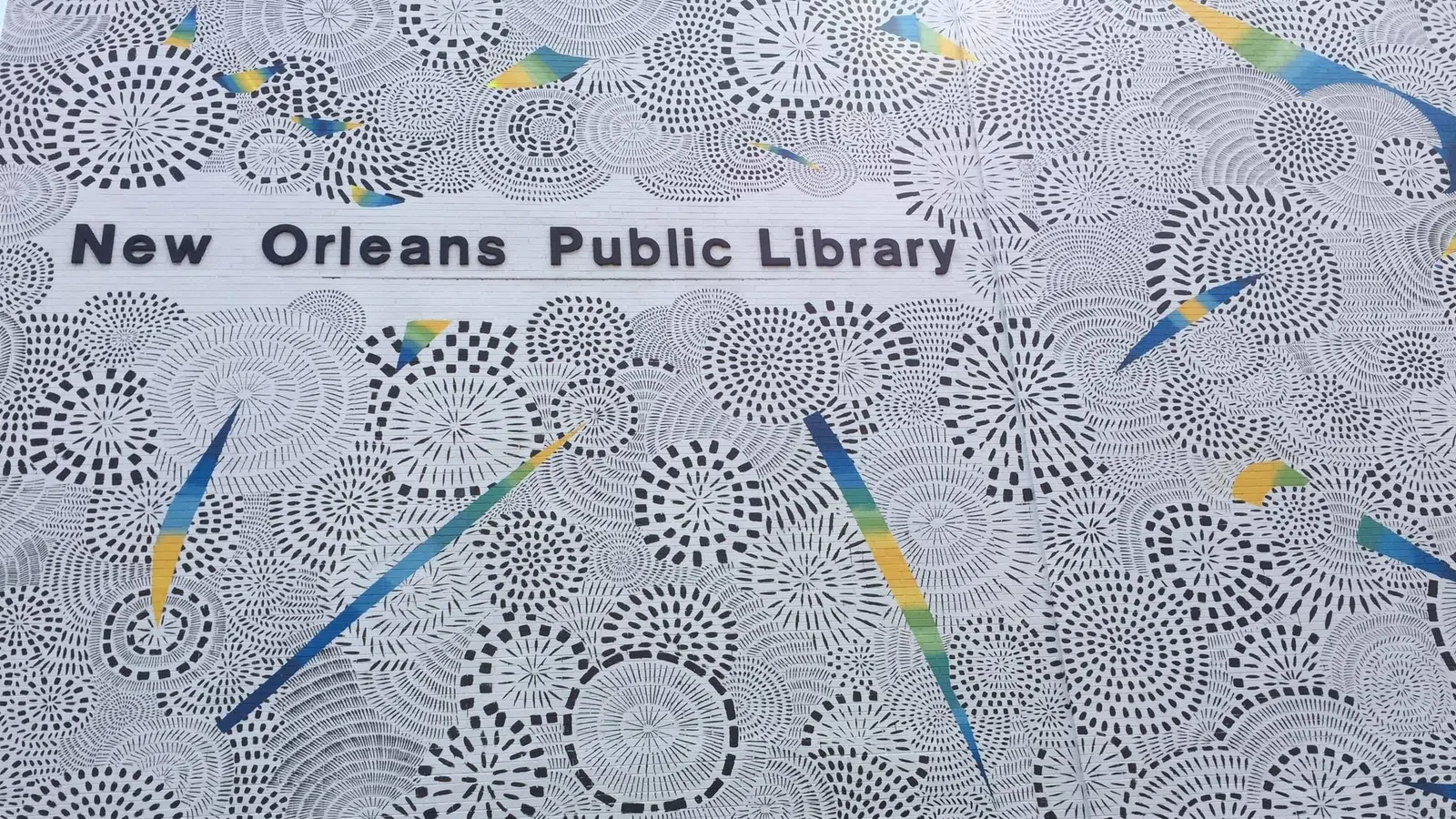 Intricate circular patterns with colorful geometric shapes surrounding New Orleans Public Library text.