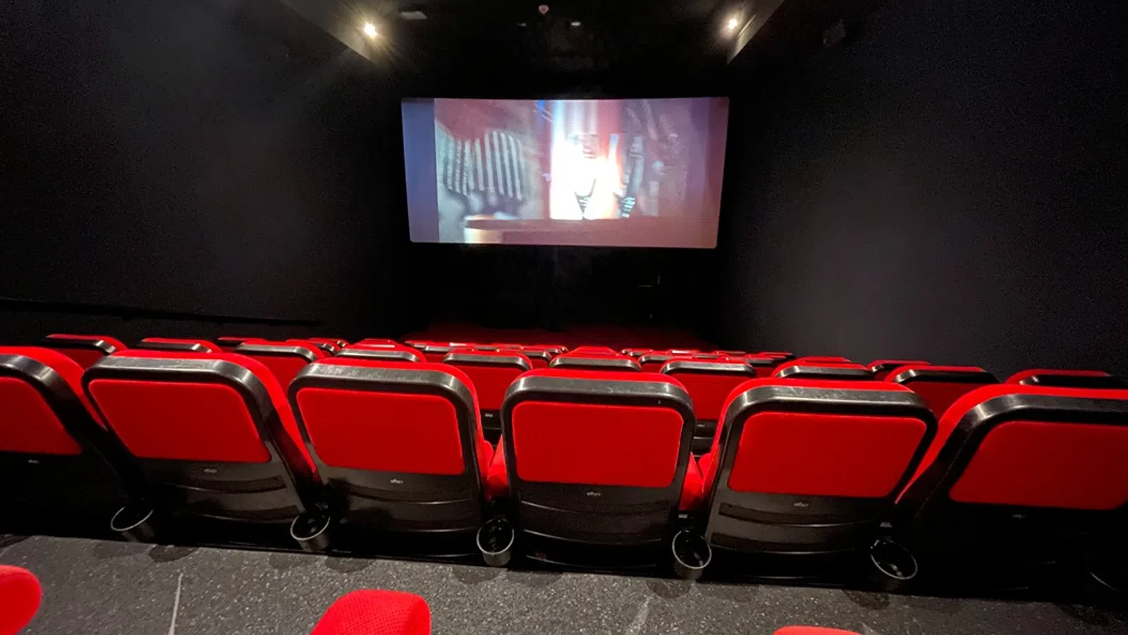 a large room with red chairs and a tv on the wall