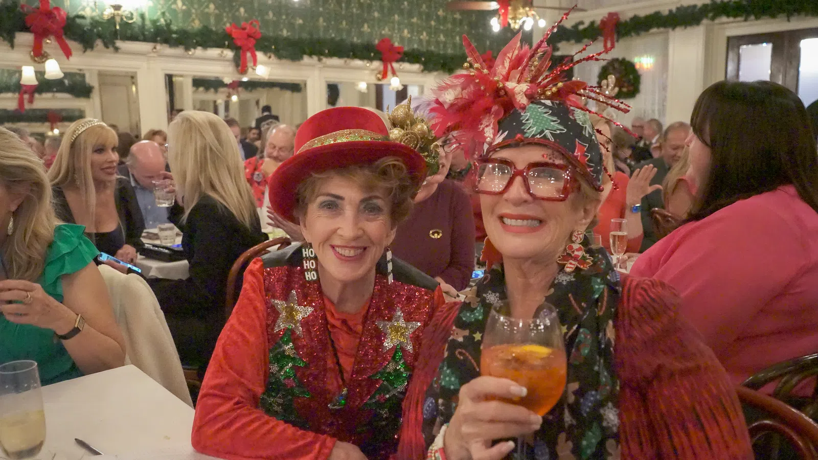 a couple of women wearing red hats and holding drinks