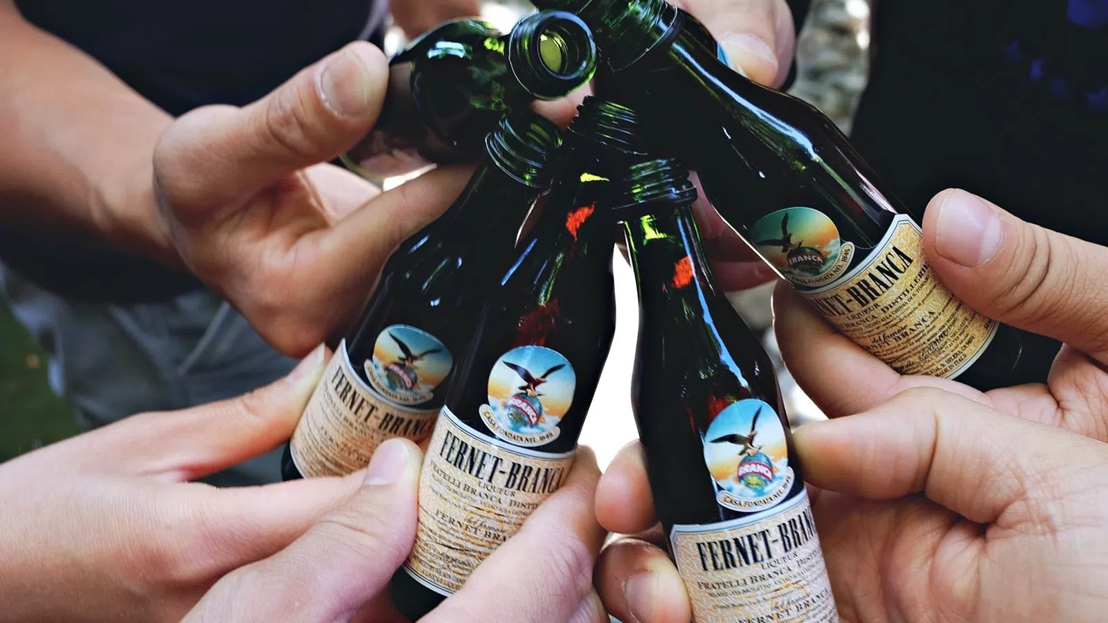 a group of hands holding bottles