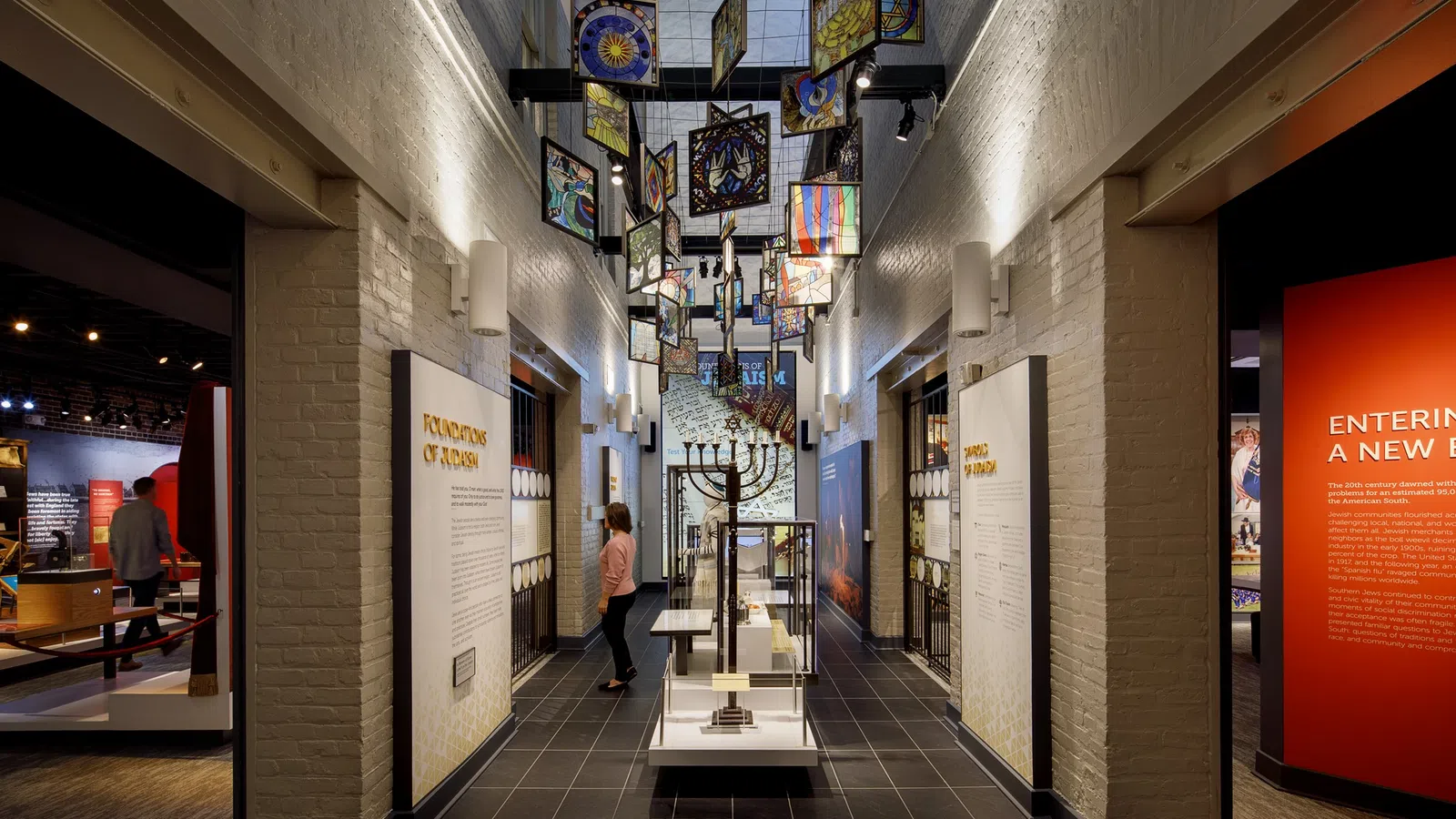 A museum hallway with hanging art pieces and informative displays on both sides.