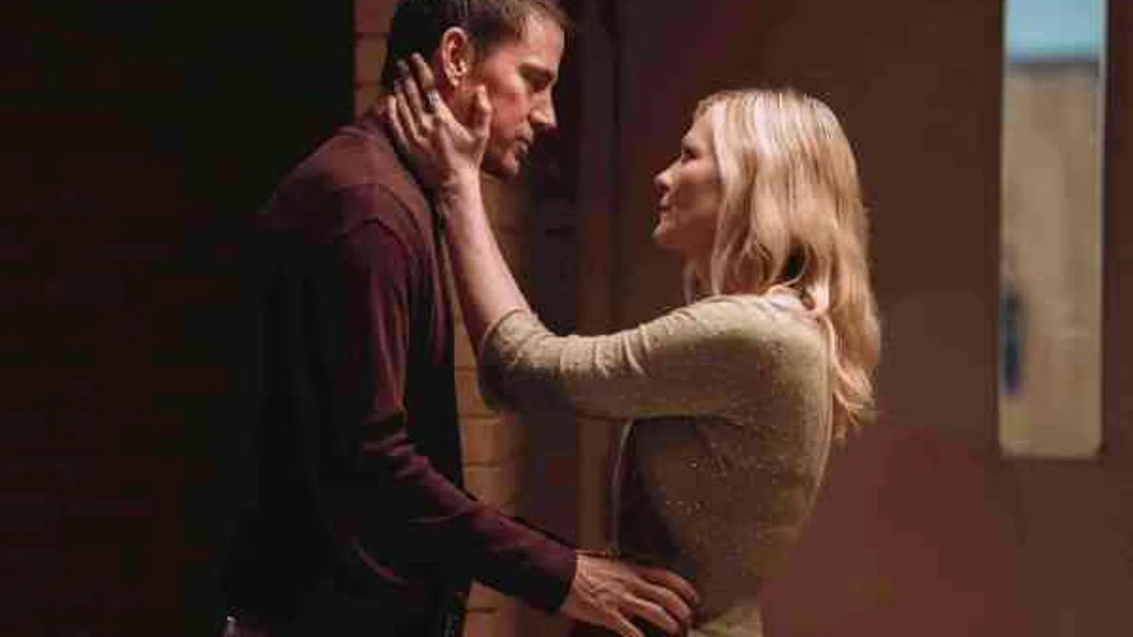 Couple sharing an intimate moment in a dimly lit room with warm tones and soft expressions