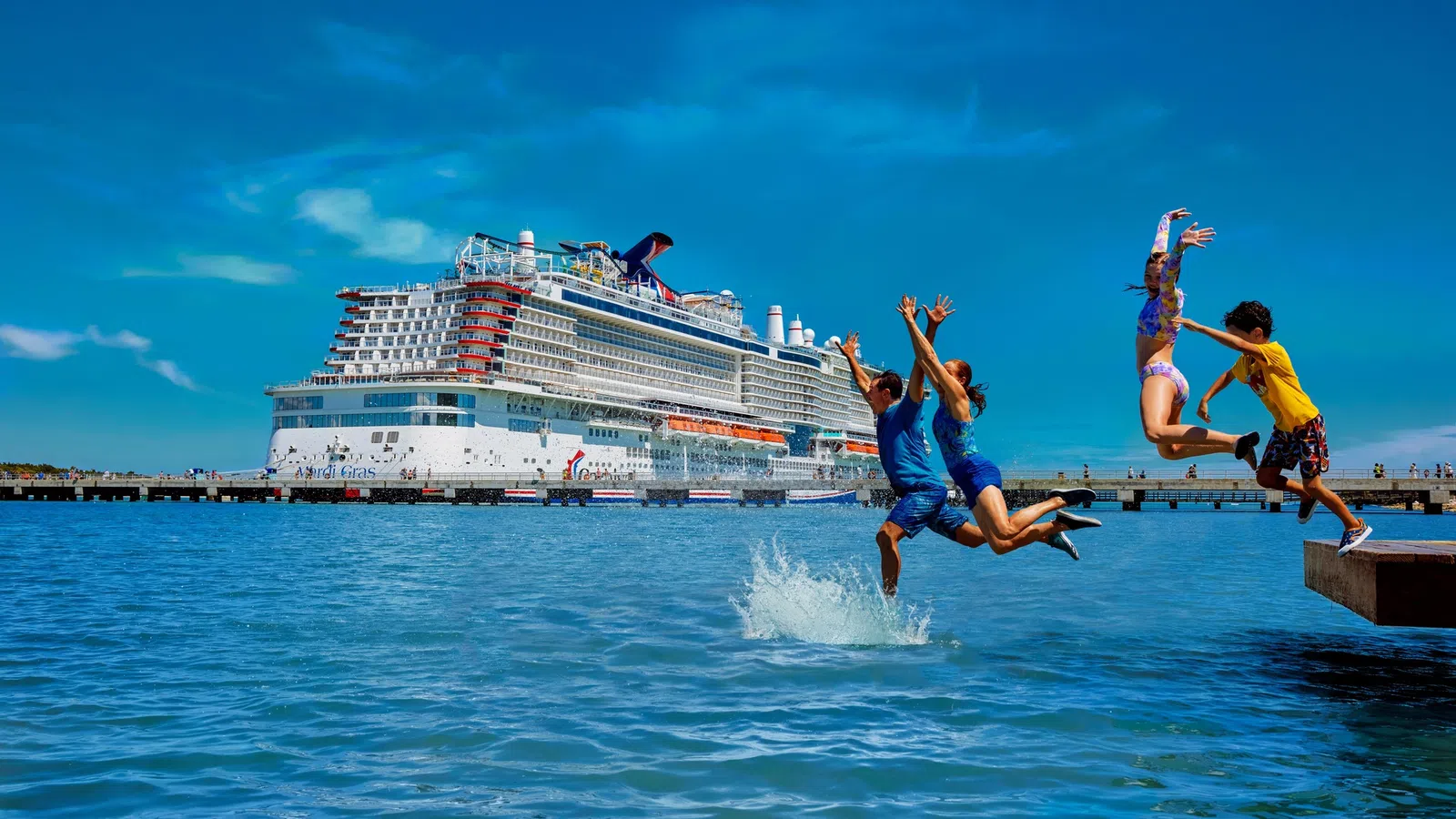 Group of children jumping into clear blue water near a large cruise ship docked at a sunny port.