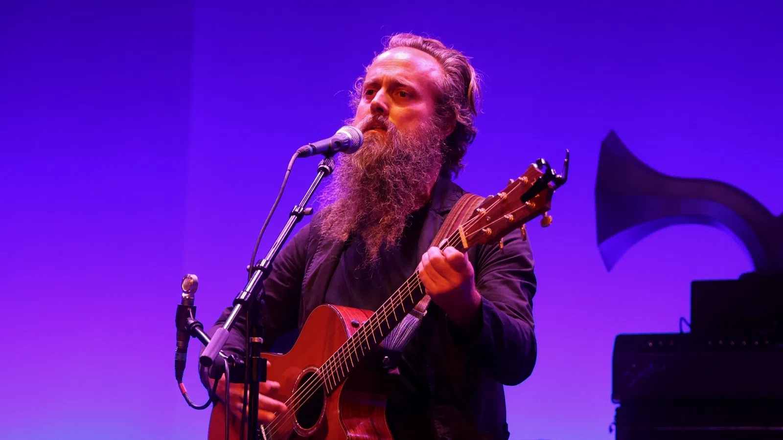 Iron & Wine playing a guitar on a stage