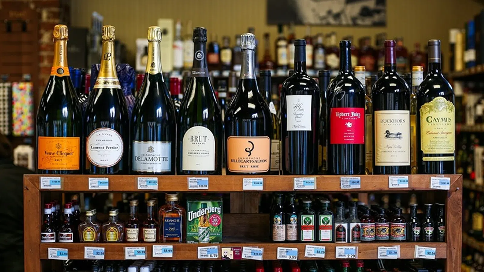 Variety of large champagne and wine bottles displayed on top of liquor shelves in a store