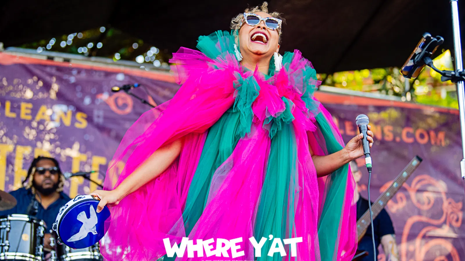 Colorful performer in vibrant costume singing on stage at a music festival.