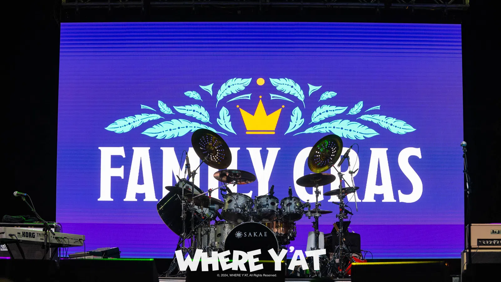 a stage with a blue screen and a drum set and a crowd