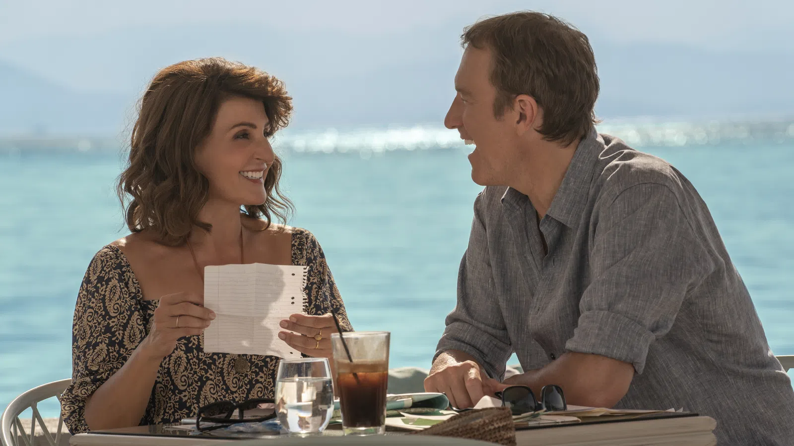 a man and a woman sitting at a table with drinks and papers