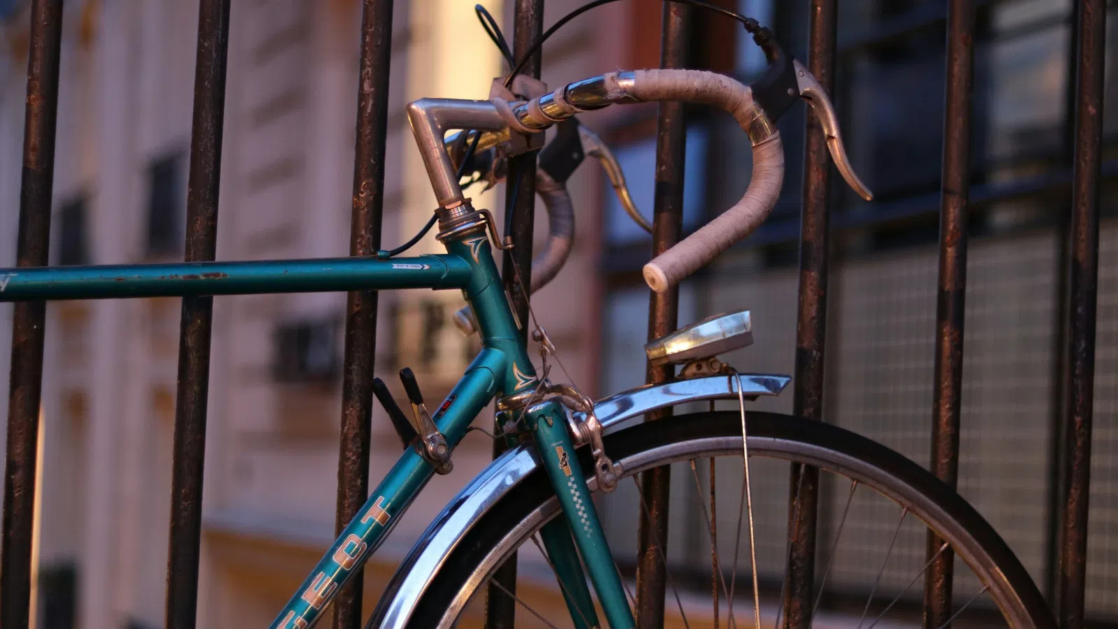 Close-up of a vintage bicycle parked against a railing during sunset.