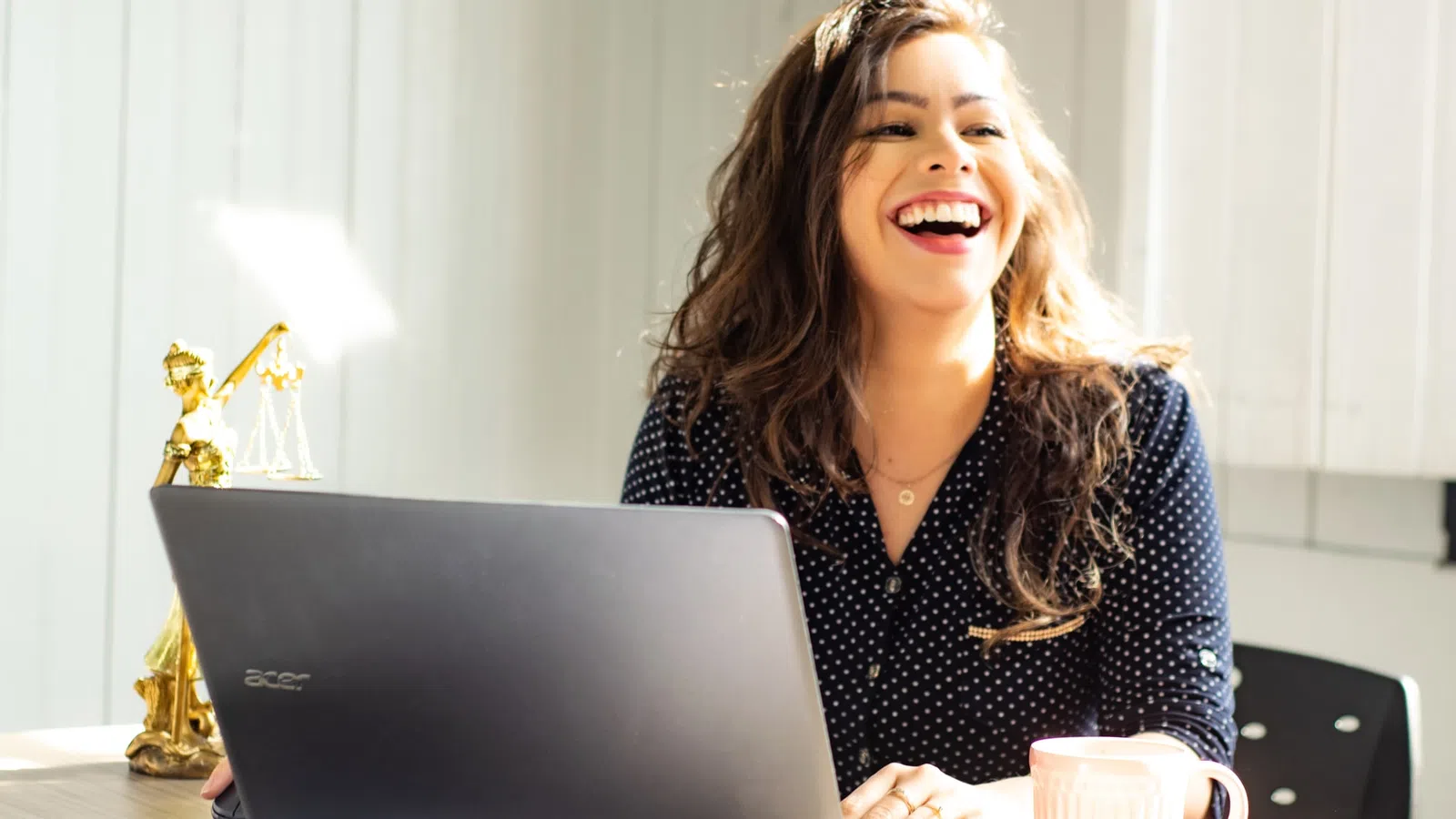a woman laughing while using a laptop