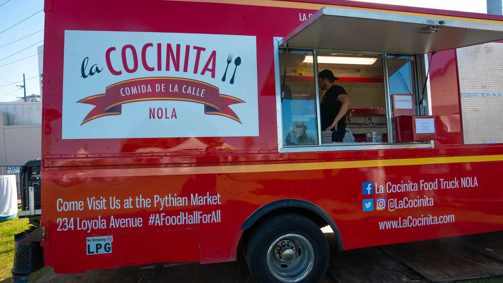 Red La Cocinita food truck parked with open service window and contact info at Pythian Market New Orleans