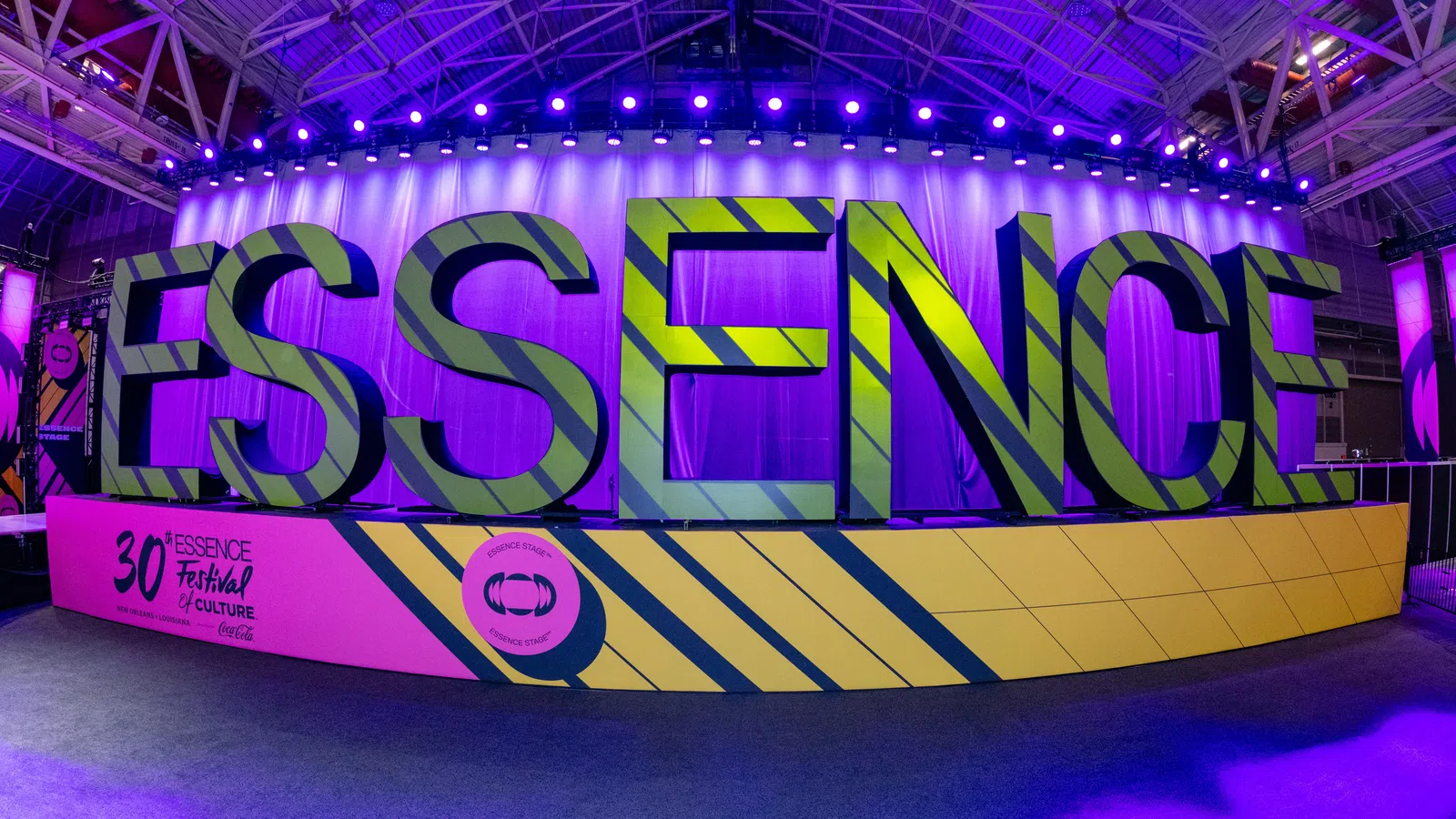 Large 3D letters spelling ESSENCE at the 30th Essence Festival with purple lighting in a convention hall.