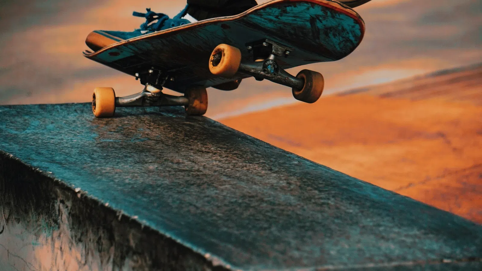 Close-up of skateboard wheels grinding on a concrete ledge during a sunset skate session.