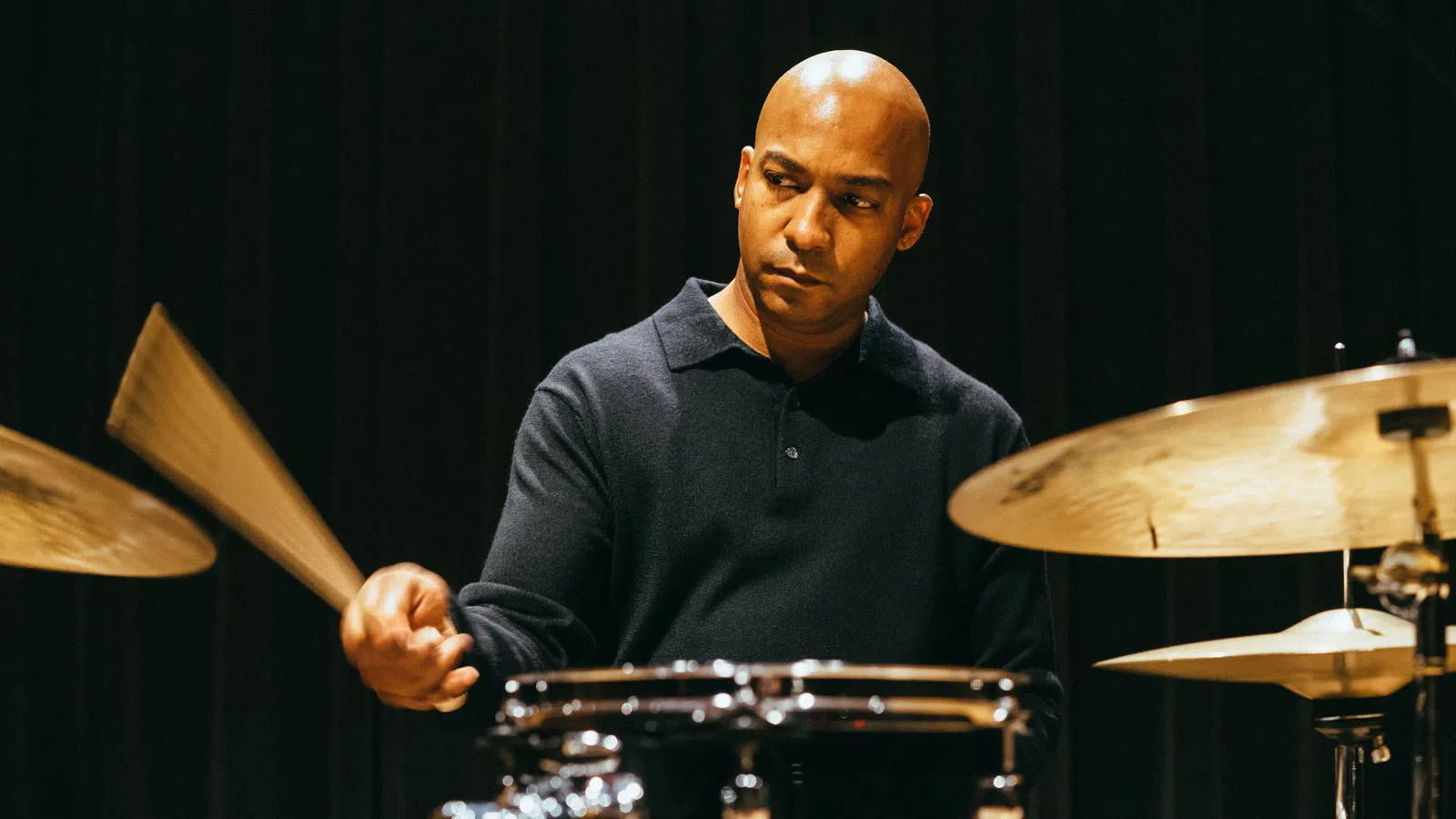 A focused musician playing drums, capturing rhythm and passion in a live performance setting.