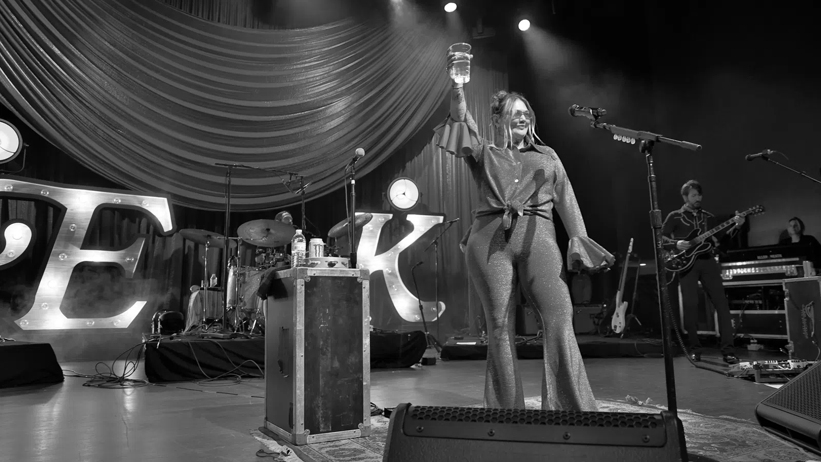 a person on a stage with a microphone and a guitar