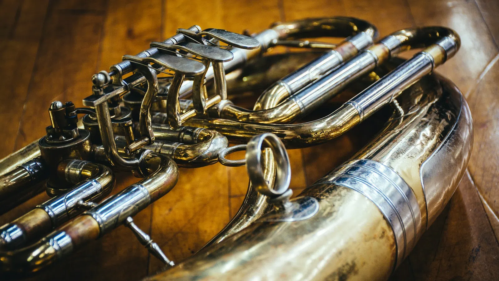 Close-up of a brass saxophone with detailed keys and tubing on a wooden surface, highlighting its polished metal.