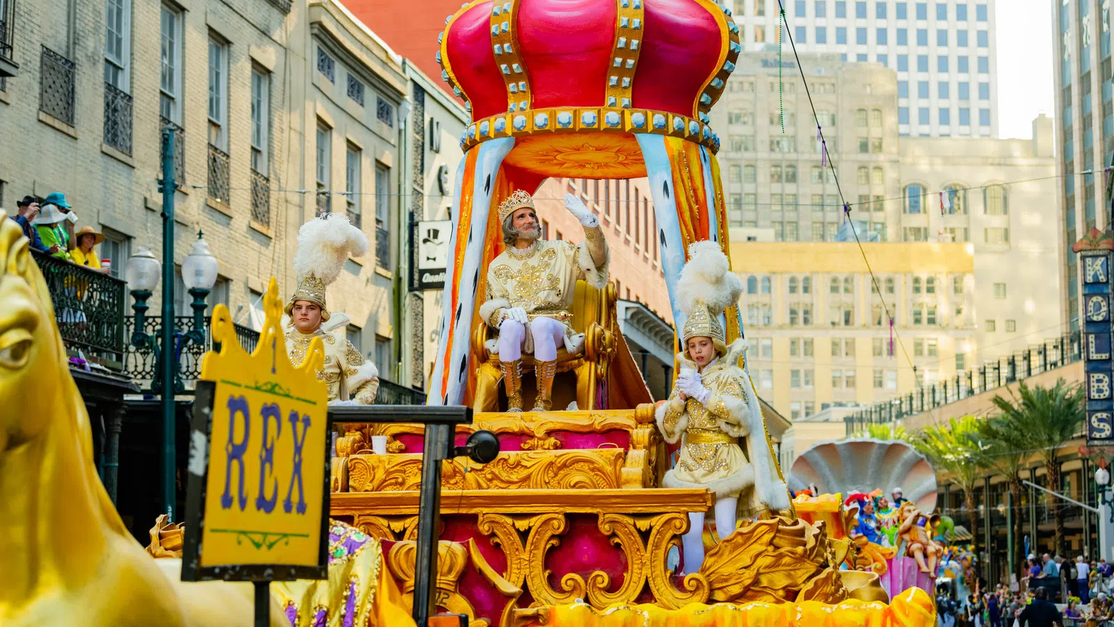 Royal procession float with King Rex and attendants in ornate gold costumes during city parade.
