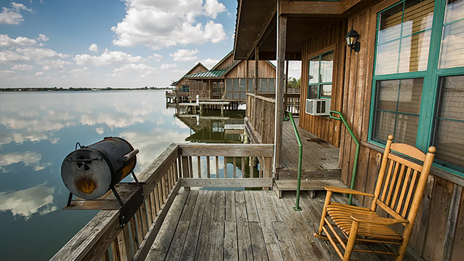 a wooden dock with chairs and a grill on it