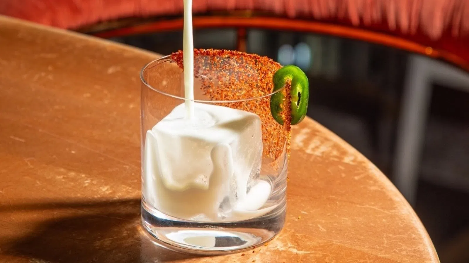a person pouring a drink into a glass