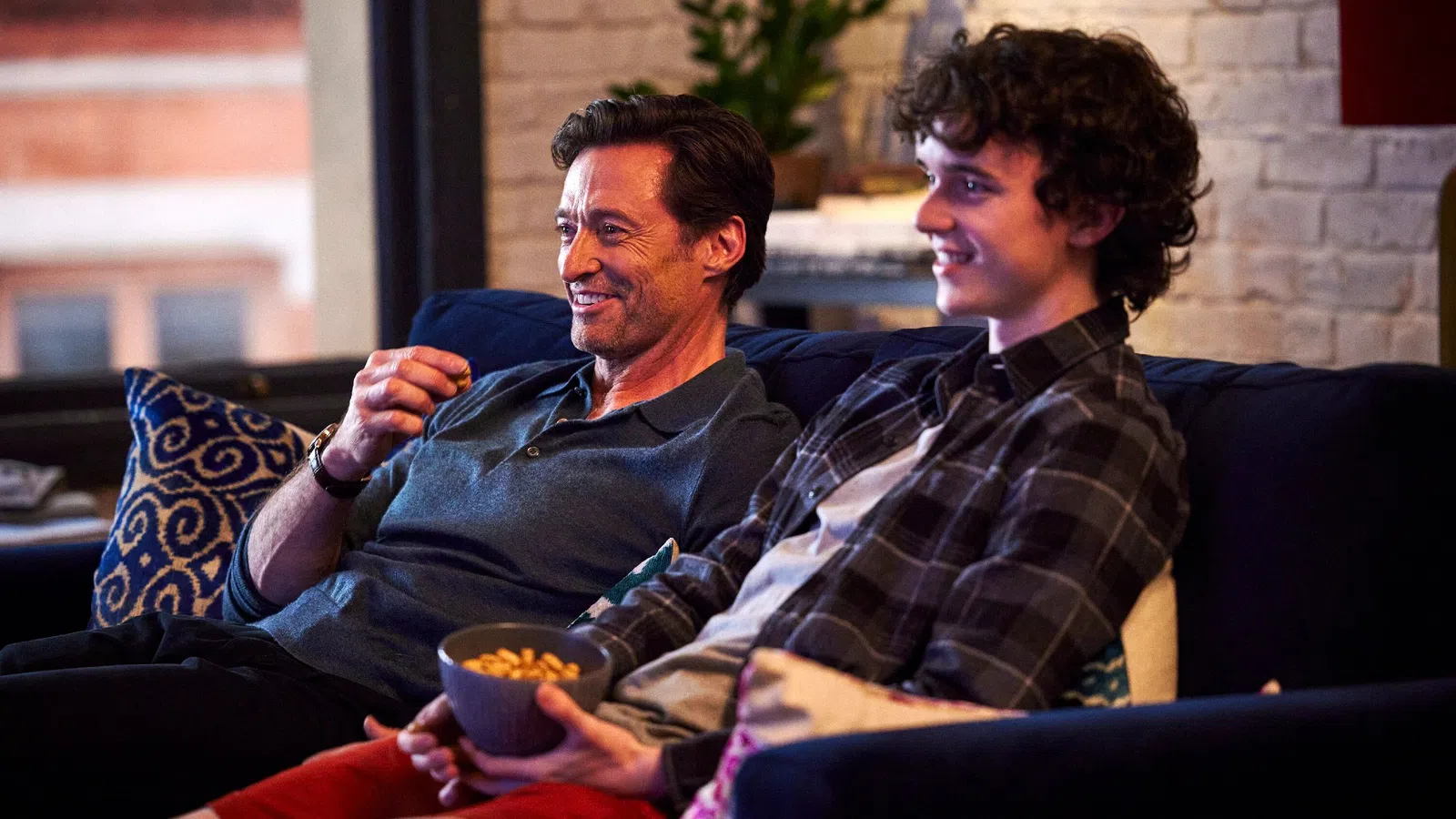 Hugh Jackman et al. sitting on a couch and smiling