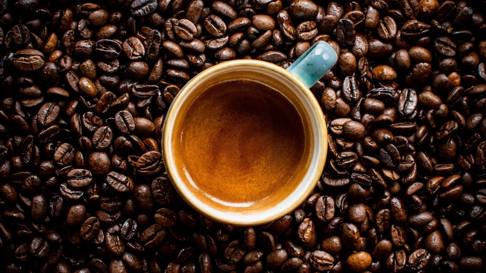a cup of coffee on a coffee beans