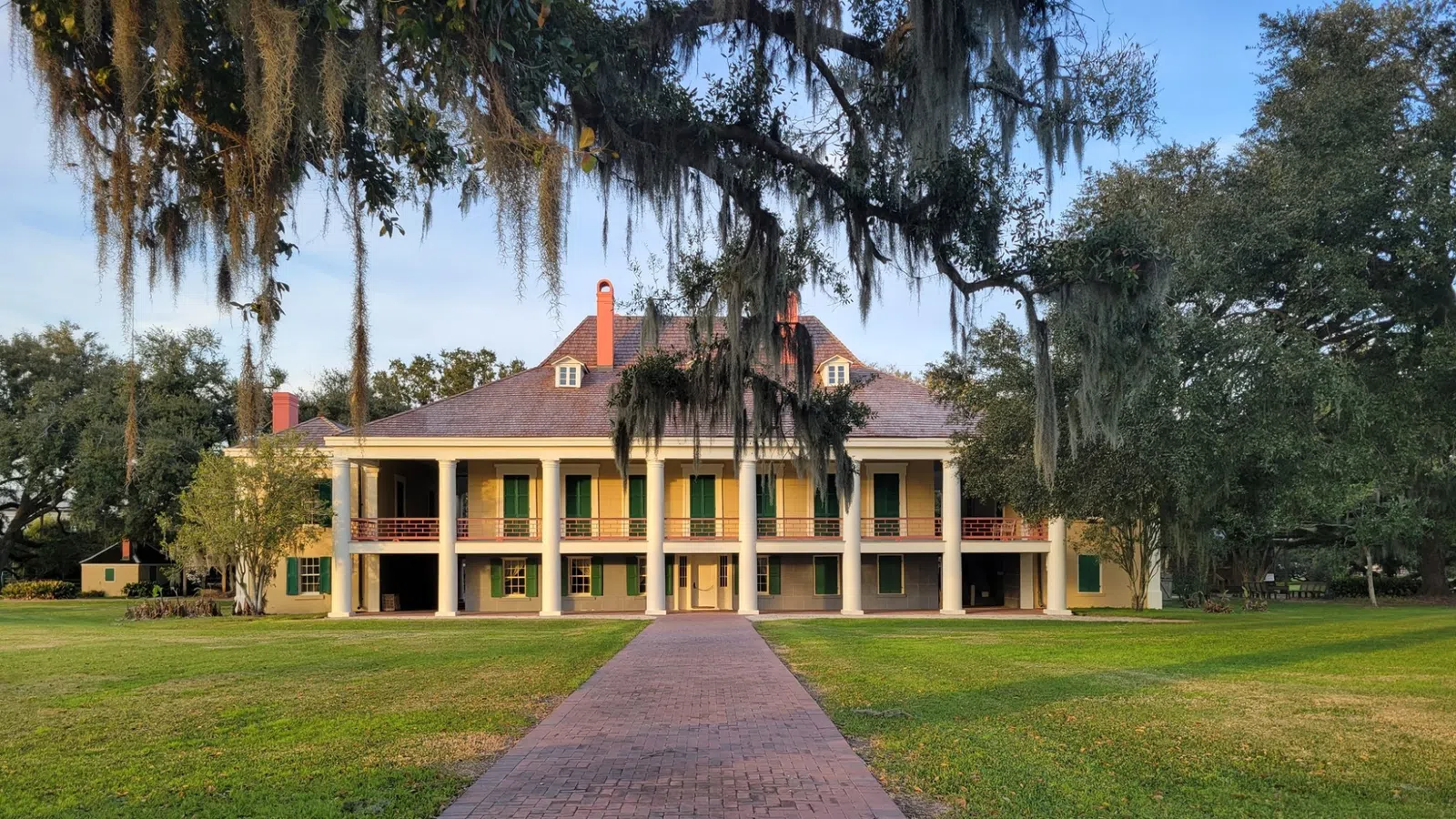 a brick path leading to a house with Destrehan Plantation in the background