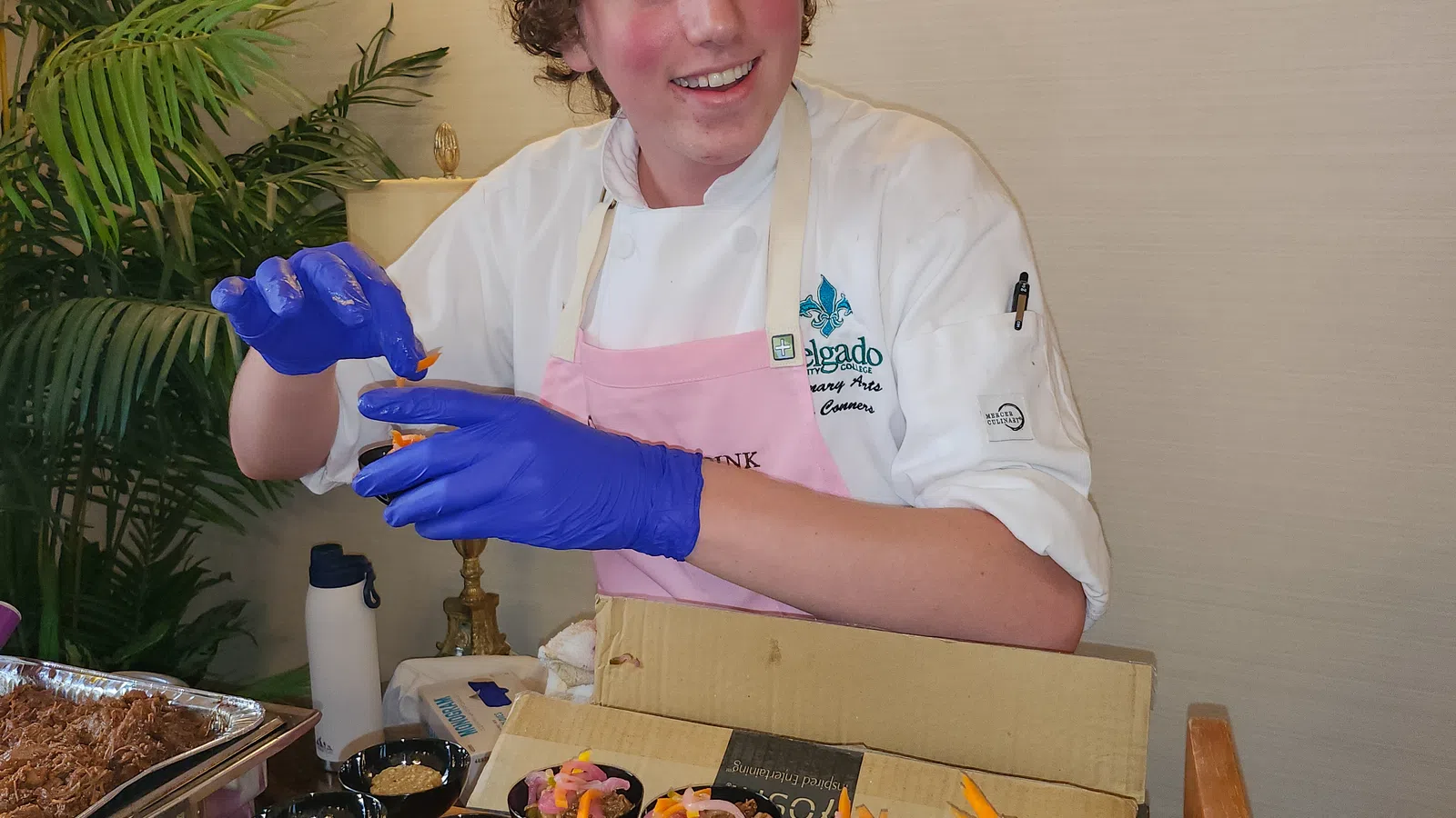 a person wearing a chef's outfit and gloves standing next to a table full of food