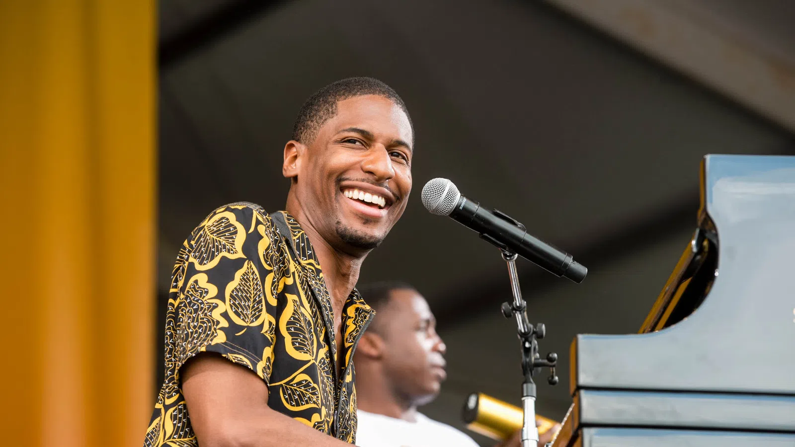 Smiling musician playing piano and singing into microphone during live outdoor performance