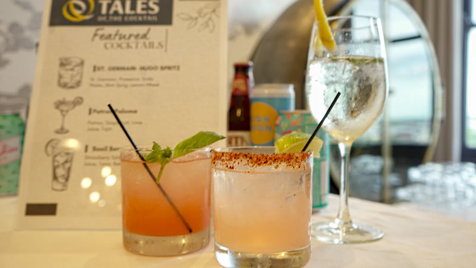 Three cocktails on a table with a menu in the background at Tales on the Crescent bar
