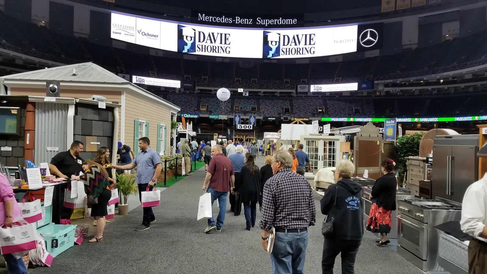 Visitors explore home and kitchen exhibits at an indoor trade show in Mercedes-Benz Superdome.