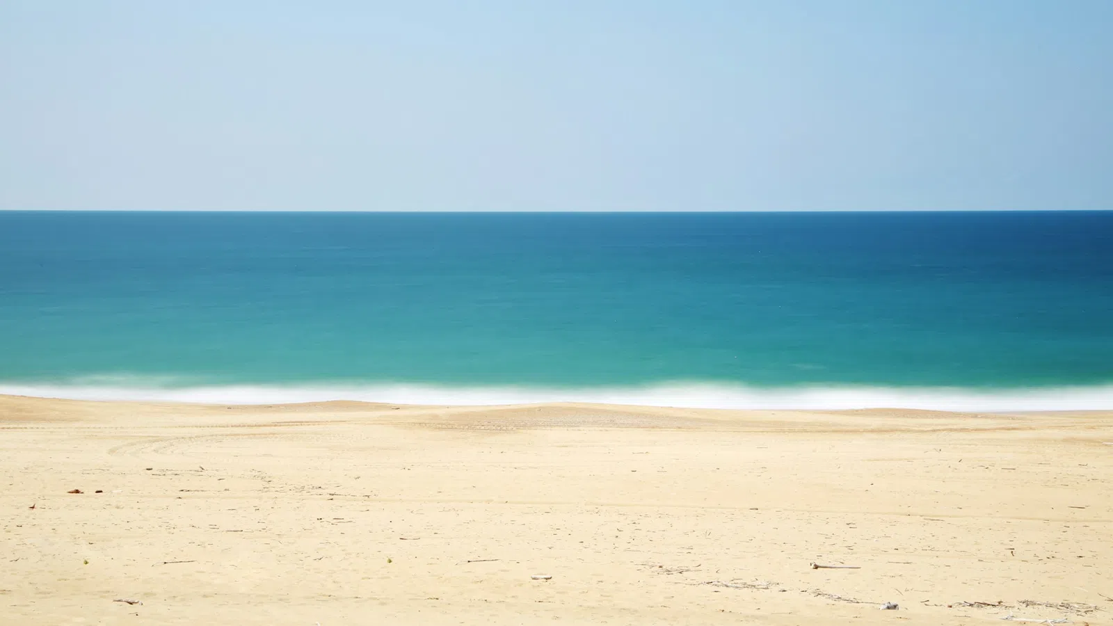 a sandy beach with blue water