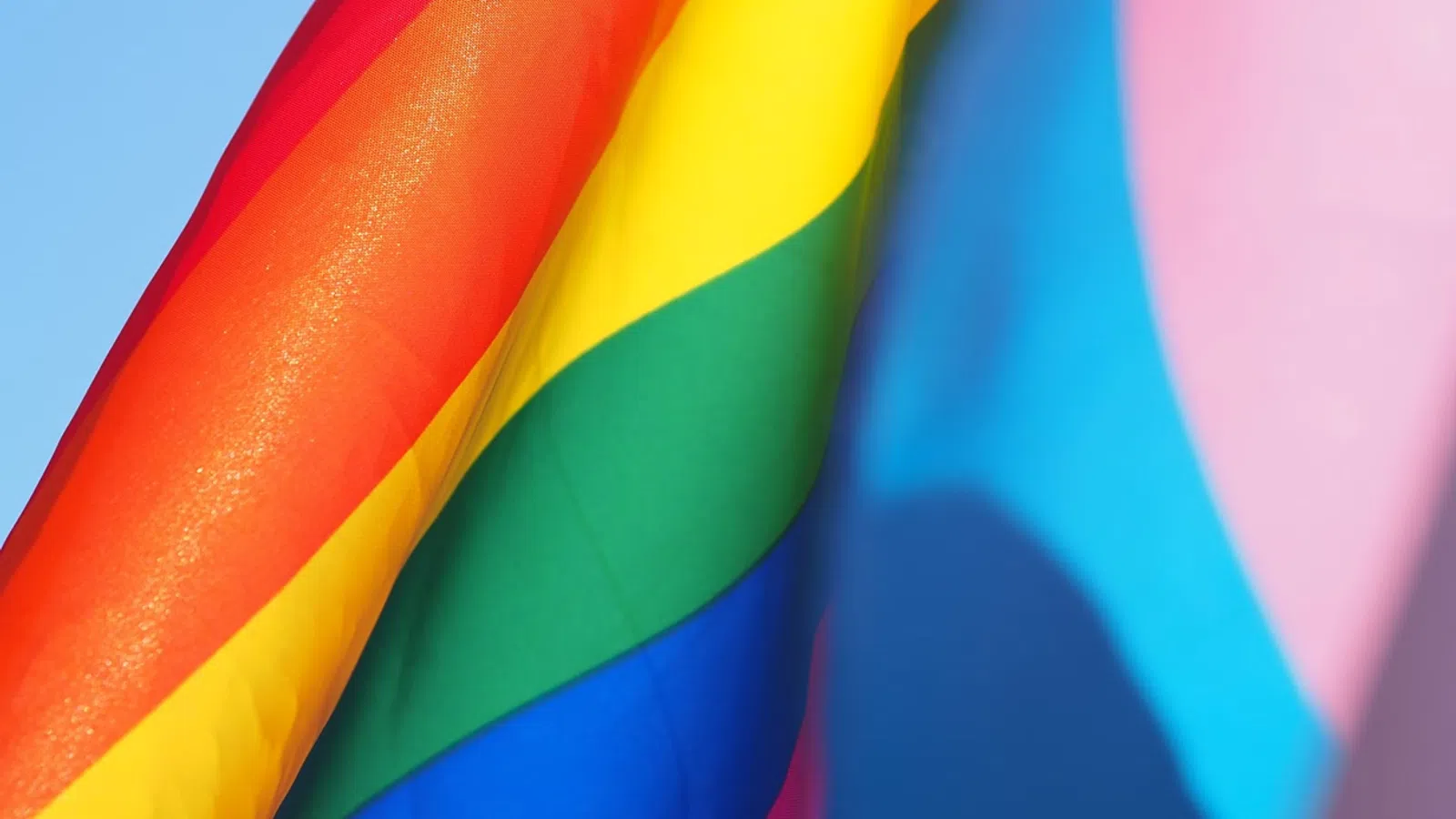 Close-up of a vibrant rainbow pride flag waving with bright red, yellow, green, blue, and pink colors.