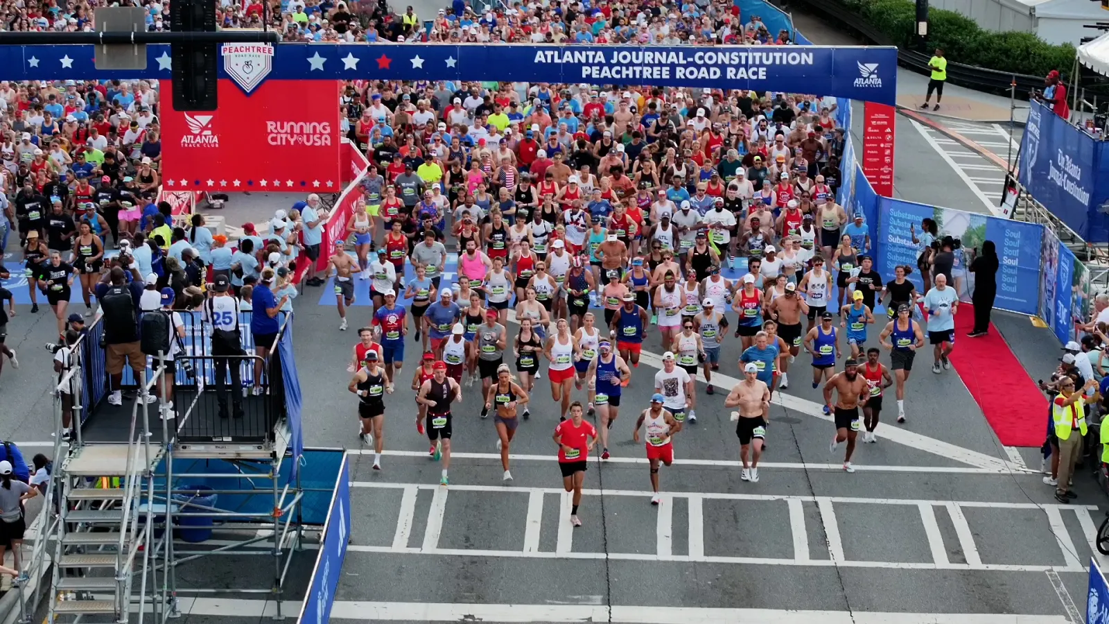 Crowd of runners at the start of the Atlanta Journal-Constitution Peachtree Road Race on city street.