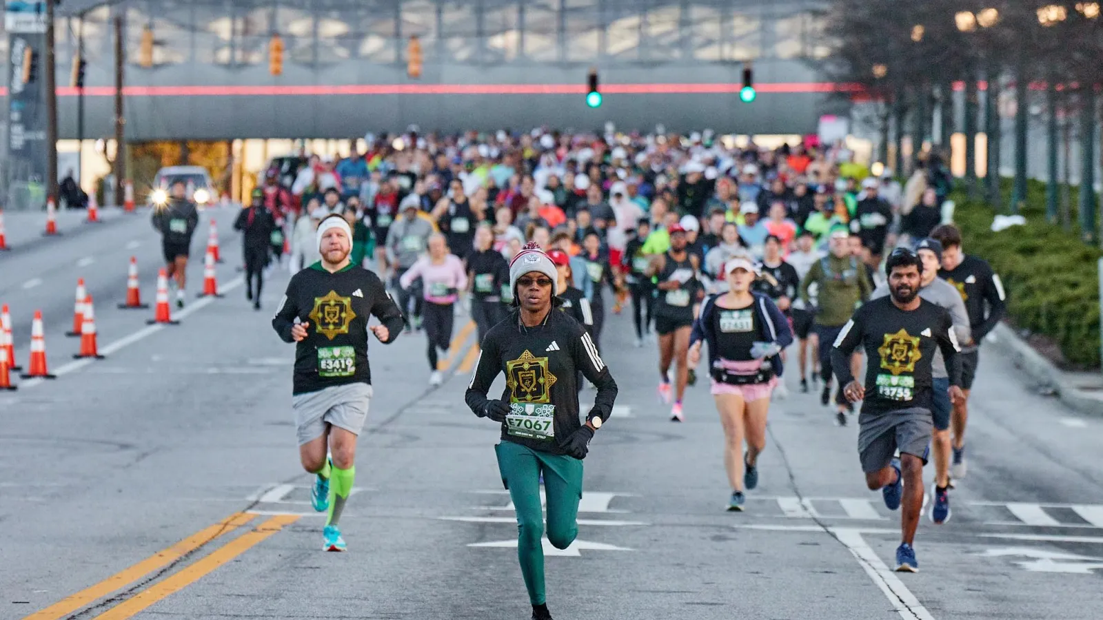 a group of people running on a street with a crowd watching