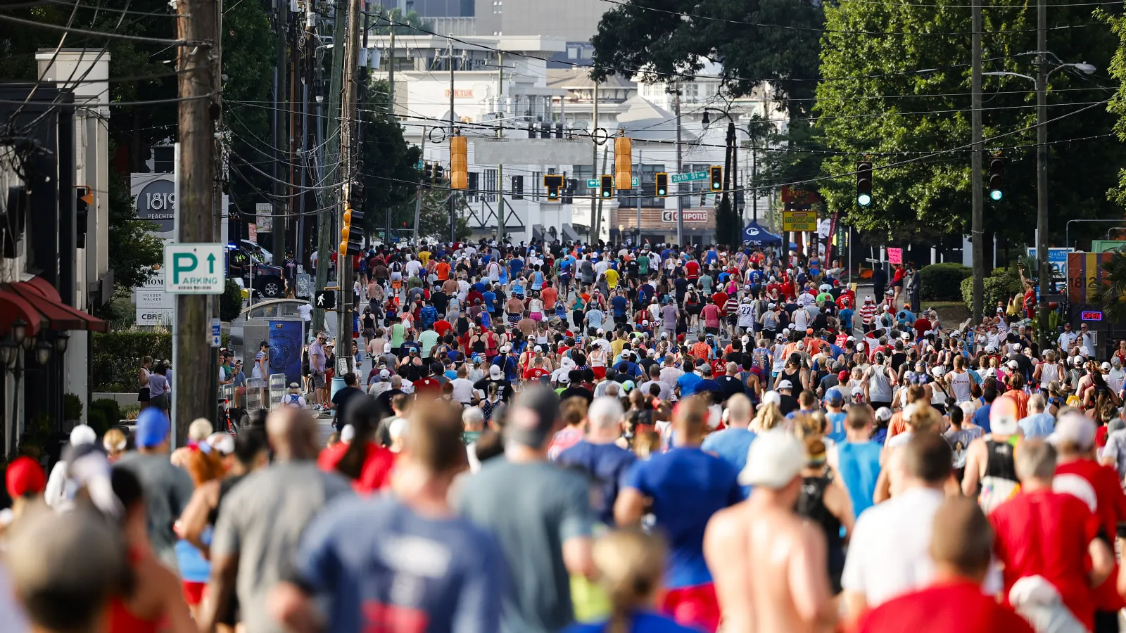 Large crowd of runners participating in a city marathon with urban buildings and traffic lights in the background
