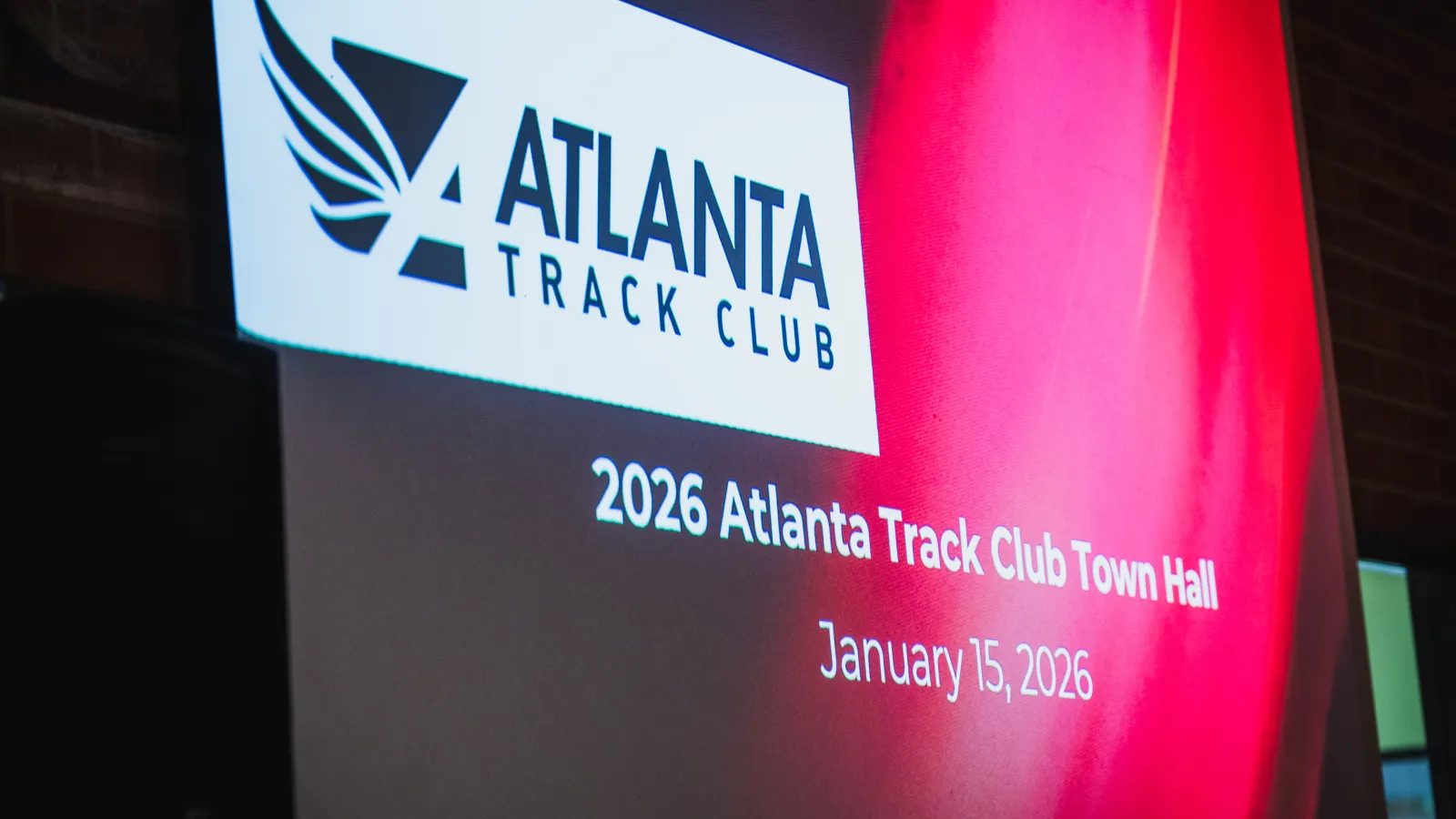 Projection of Atlanta Track Club logo and 2026 Town Hall event dated January 15, 2026, on a red background.