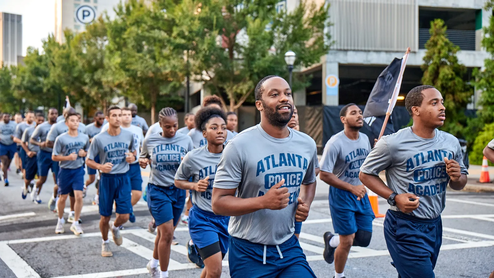 Group of Atlanta Police Academy cadets jogging together outdoors during training session in the city.