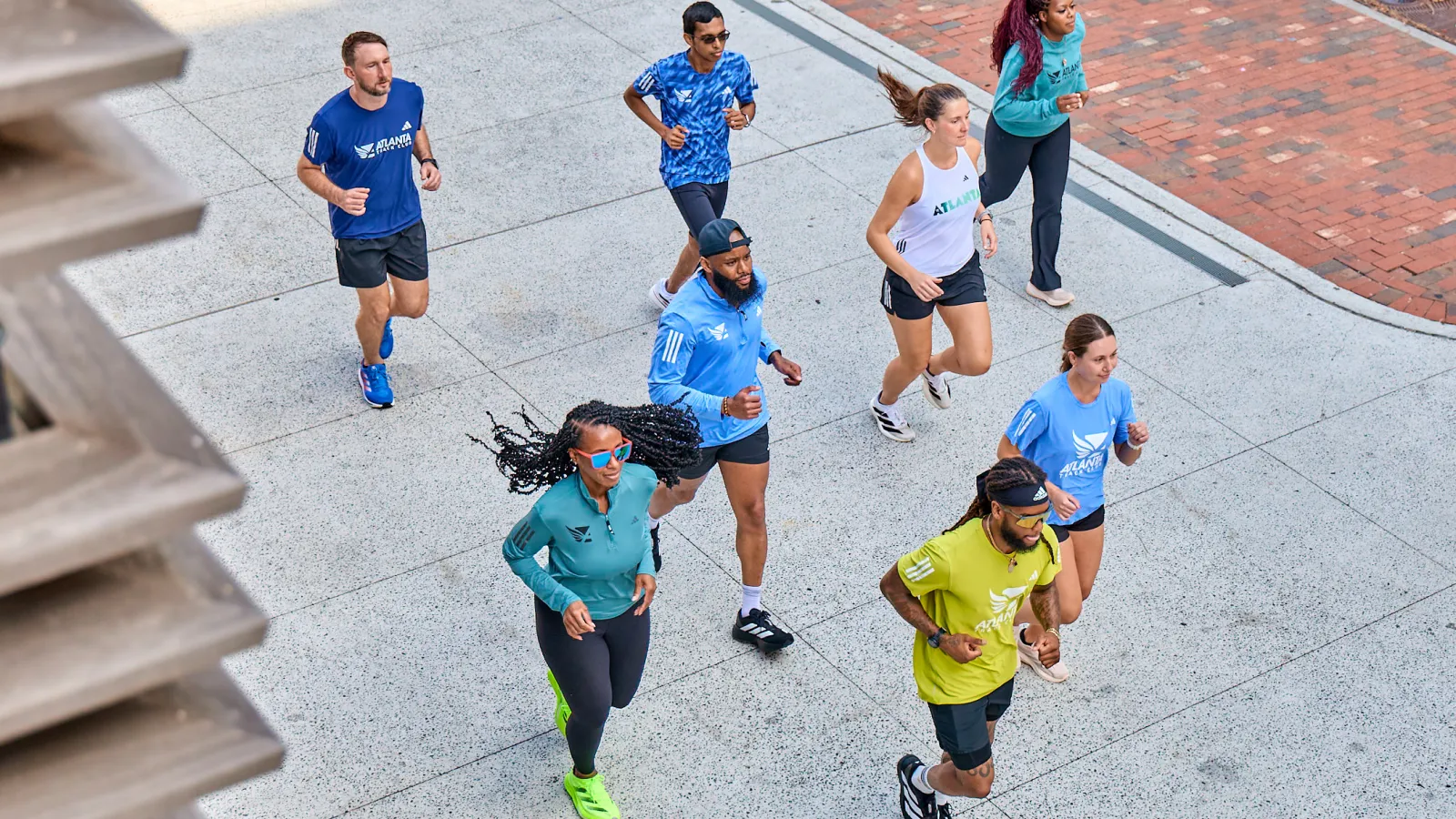 Group of diverse people jogging outdoors on a sunny day wearing athletic wear and running shoes.