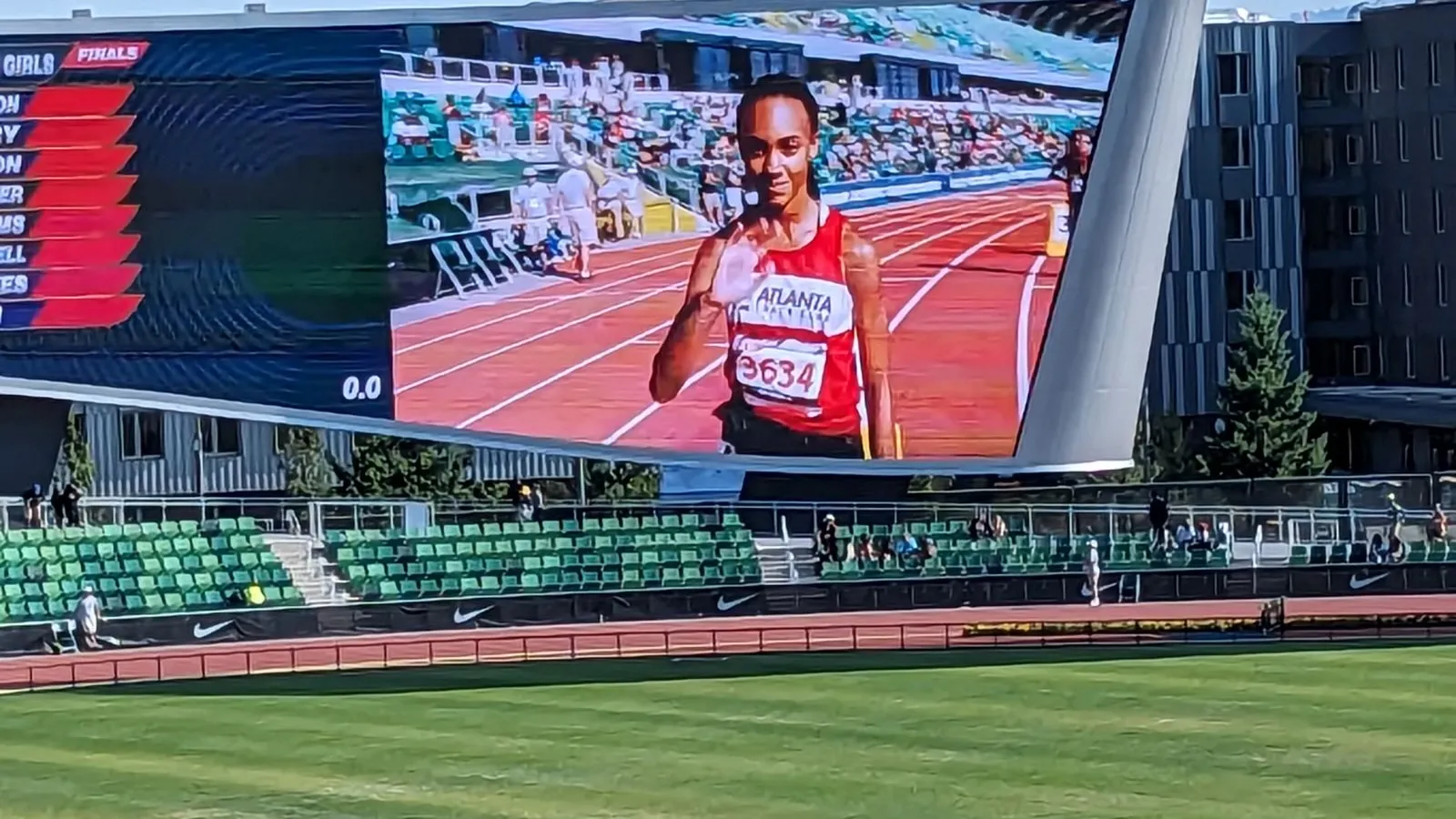 a person in a sports uniform on a football field with a large screen behind him