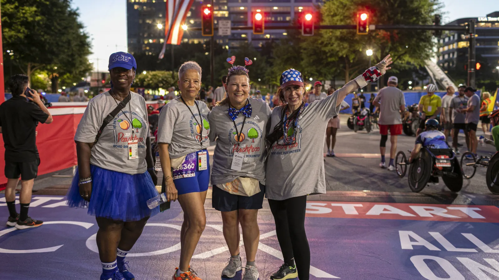Four joyful participants at a colorful race start line, celebrating in festive attire.