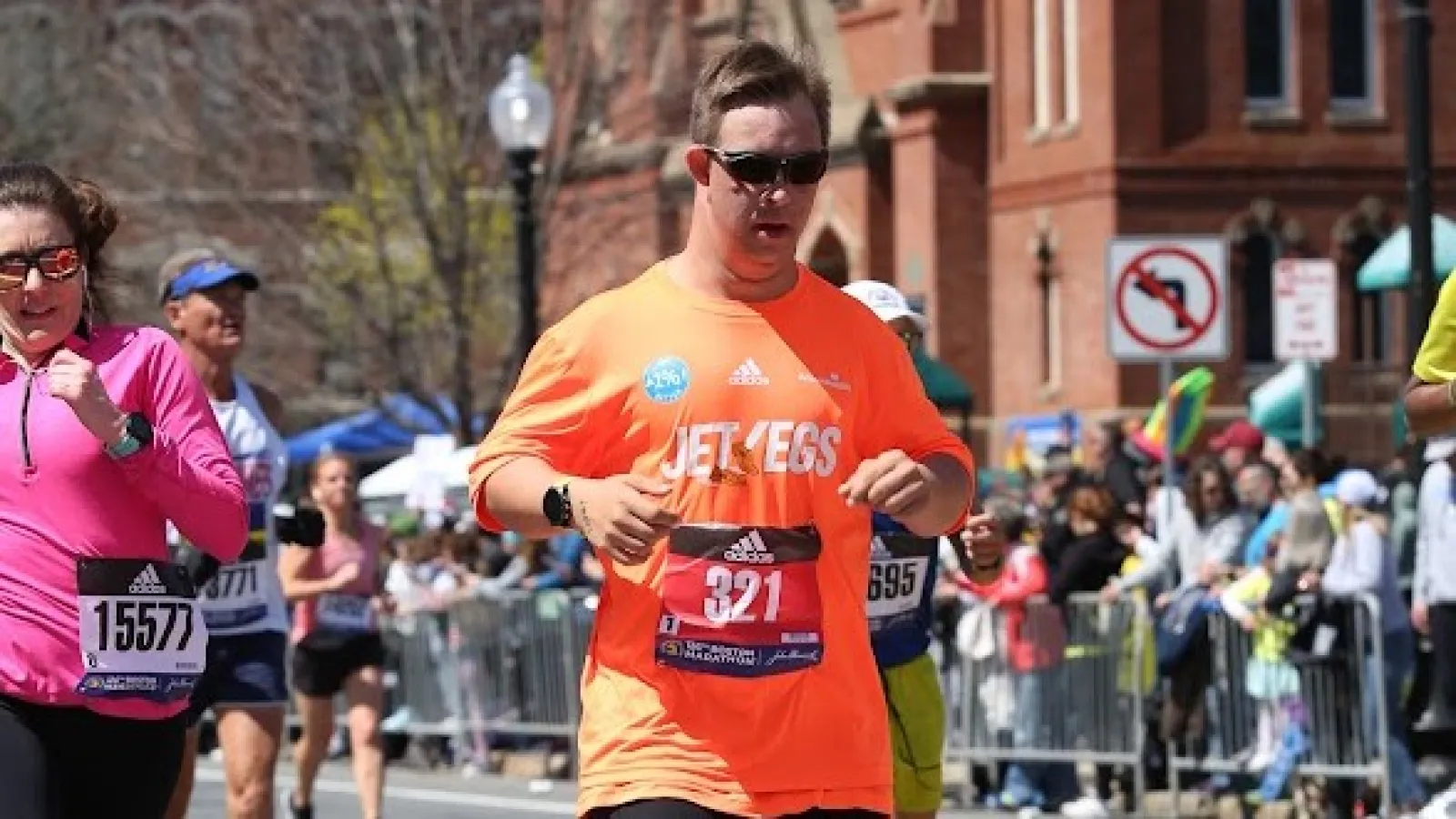 Chris Nikic runs the Boston Marathon in 2022 wearing an orange adidas shirt reading "Jet Legs" and an adidas "Runner 321" bib